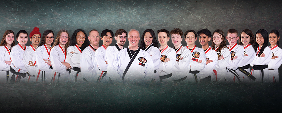 Group of martial arts students in white gi with belts, lined up with the instructor in the center.